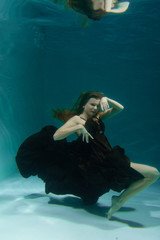Fototapeta na wymiar Hot Slim Caucasian Woman Posing Under water in beautiful clothes alone in the deep