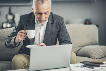 Elderly businessman reading morning news on laptop