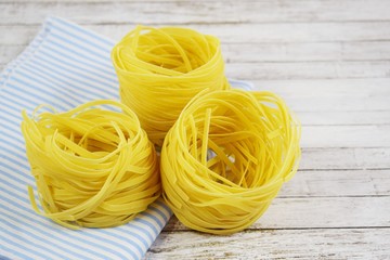 Pasta in the shape of a nest on a wooden background.