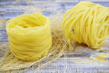 Pasta in the shape of a nest on a wooden background.