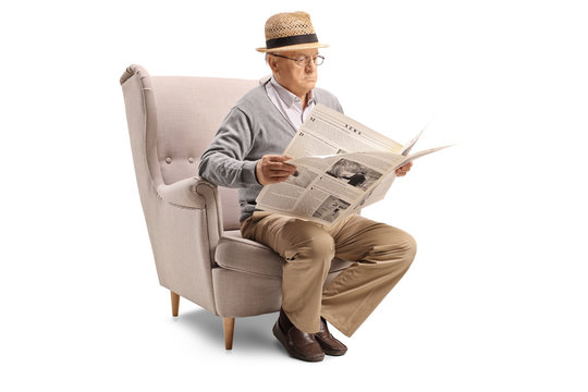 Senior man sitting in an armchair and reading a newspaper