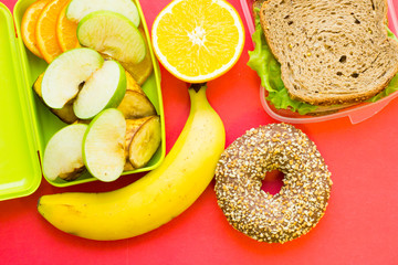 School lunch box. Bread, orange, baby corns, carrot and tomatoes in green plastic container
