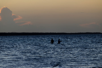 People fishing in the ocean at sunset in the Caribbeans