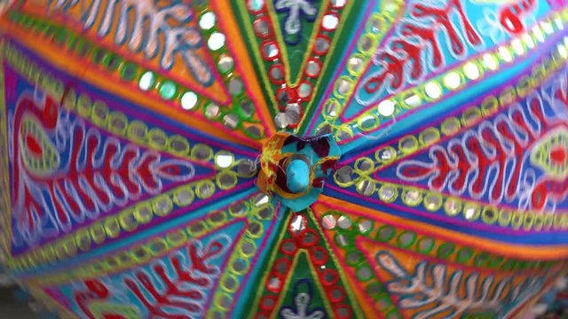 Beautiful umbrella or parasol highly decorated with intricate embroidery, mirror and bead work in Pushkar, Rajasthan, India. Colorful umbrella rotates with the hands, close up