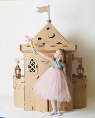 Beautiful little girl in princess dress playing with her toy castle.