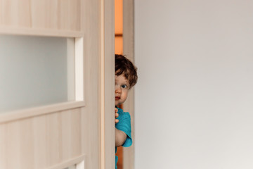 little kid hiding behind the door playing hide and seek