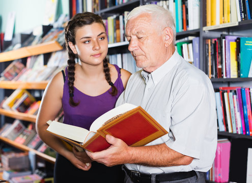 grandfather with girl are choosing books