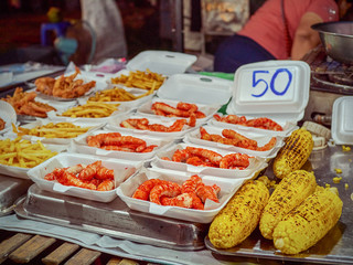 Street food in Thailand. Shrimps in foam containers, corn, french fries and other food