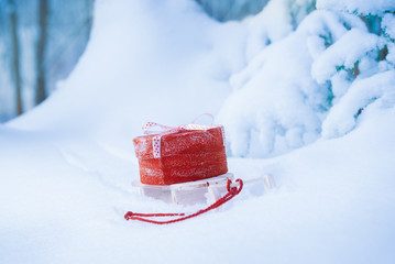 Red gift box on sleigh in snowy winter forest