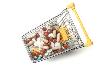 closeup of drup pils and capsules in supermarket trolley on white background