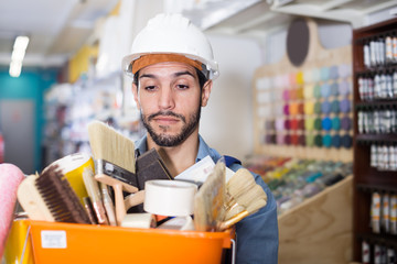 Young workman holding basket with picked tools