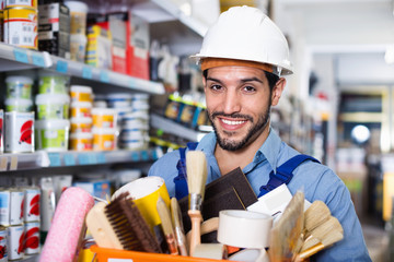 Workman holding basket with picked tools in paint store