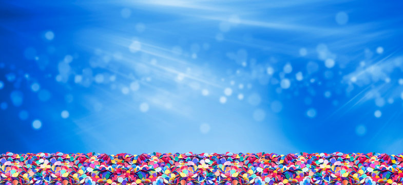 Colorful confetti in front of blue background with bokeh for carnival