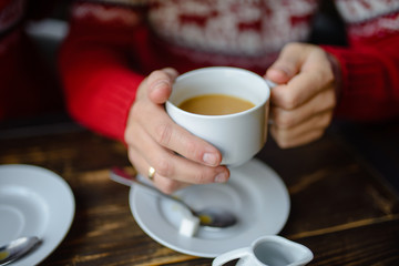 Couple holding knitted coffee cups dressed in sweater