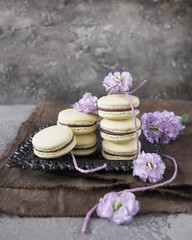 Fototapeta na wymiar Yellow cake macarons with lilac flowers