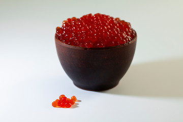 red caviar in a ceramic dish on a wooden platform on a white background