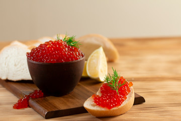 red caviar in a ceramic dish on a wooden background in a rustic style with space for text