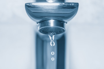 Faucet and drops close up on blue background