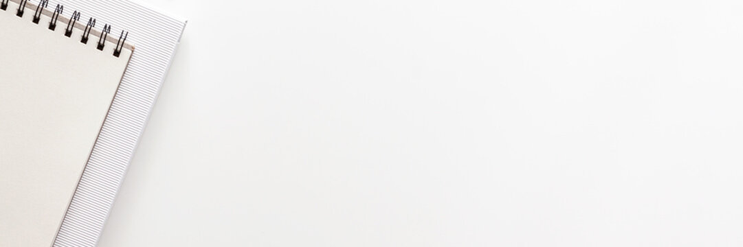 White office desk with empty space for text. Copy space. Office accessories such notebook and paper. Panoramic view from the top. Black and white composition. High key