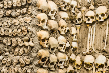 Human bones and skulls are embedded in the wall. Texture.