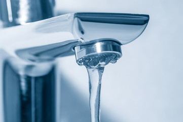 Metal tap with flowing water close up