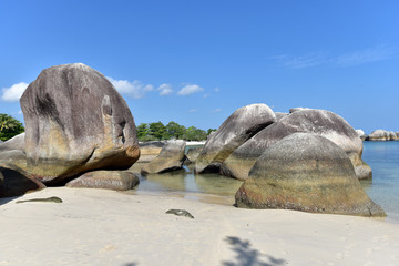 Natural rock formation in the sea at the Tanjung Tinggi Beach in Belitung Island in the afternoon and a white sand beach at the background, Indonesia