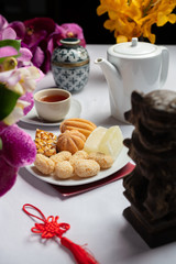 Concept picture of Chinese New Year traditional food with tea pot in background. Variety of cake, pine and other sweet.