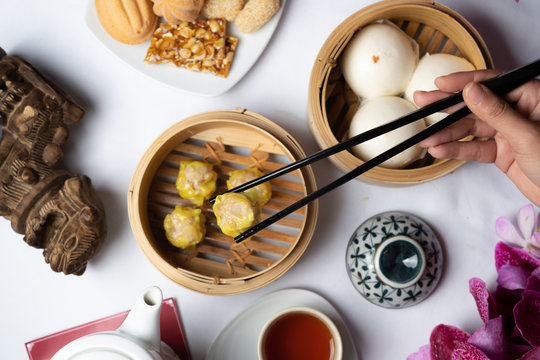 Concept picture of Chinese New Year food. Dim Sum on table with hand holding chopstick