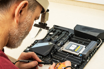 Male tester checks the circuit of the motherboard. The concept to assemble a computer at home. Copy...