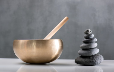 Klangschale und Steinmännchen vor grauem Hintergrund, Balance und Klang , innere Ruhe und Energie