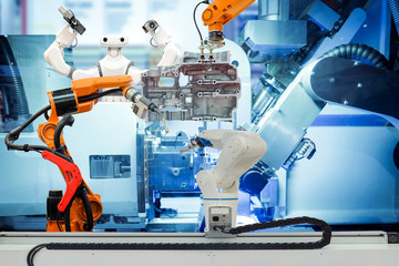 Industrial robotic welding, robot gripping and smart robot working on smart factory, on machine blue tone color background, industry 4.0 and technology, smart robotic working on teamwork concept.