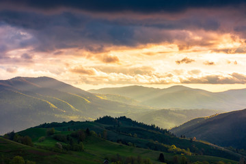 Fototapeta premium wonderful countryside in springtime at sunset. gorgeous cloudscape above the the rolling hills in rural area. fantastic view from above. distant valley in haze and evening light.