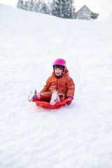 Fototapeta na wymiar A child rides a sled from a hill.