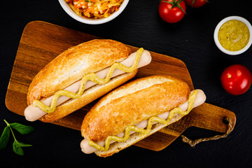 Hot dogs on cutting board on black stone plate