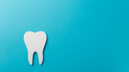 White tooth on blue background with copy space. Oral dental hygiene. Teeth whitening. Dental health...