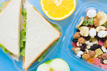 School lunch box. Bread, orange, candies, baby corns, carrot and tomatoes in green plastic container