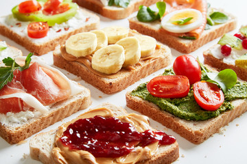Sandwiches variation with vegetables, fruits, meat, eggs and sweets viewed from above. Variety of bruchetta breads arranged for a tasty and healthy breakfast. 