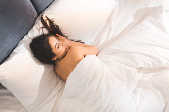 beautiful nude woman sleeping in bed at home in morning with copy space