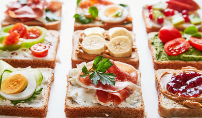 Sandwiches variation with vegetables, fruits, meat, eggs and sweets viewed from above. Variety of bruchetta breads arranged for a tasty and healthy breakfast. 