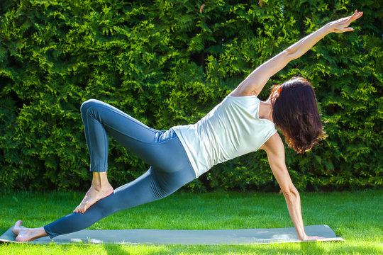 adult woman doing yoga on green grass
