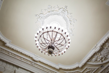 Chandelier on the ceiling of an old building. A large room or hall.