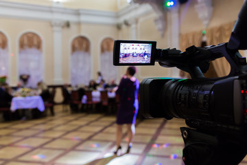 Video shooting at the event in the restaurant. Digital video camera with LCD display. People sit at...