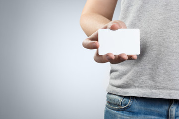 Male hand holding a blank card or a ticket/flyer on gray background