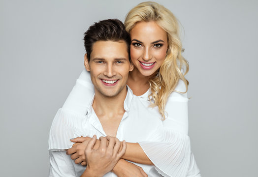 Image of lovely couple having fun, young smiling woman hugging her boyfriend isolated over gray background