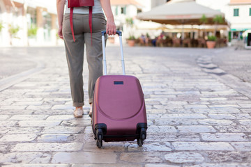 Girl traveler with suitcase arrives to old town. Woman tourist is searching direction. Concept of travel, vacation, solo female tourism, trip, journey.