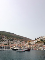 Fototapeta na wymiar Ύδρα Idra Hydra island and port overlooking the charming town among hills in a blazing summer with intense sunshine in Greece