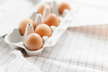 Eggs in egg tray on white kitchen towel.