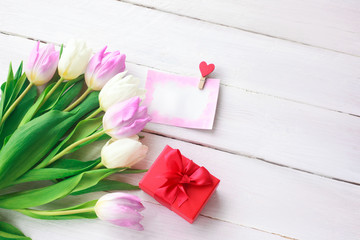 White and purple tulips and a gift in a red box on a white wooden background. Spring. International Women's Day. Valentine's Day. card ,Selective focus.