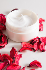 moisturizing cream and rose petals on a white