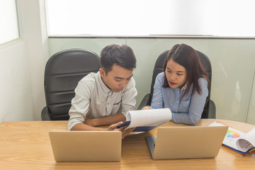 Serious conversation between two Asian employees at work